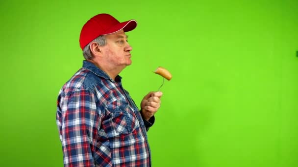 Homem Sênior Chapéu Vermelho Com Prazer Que Come Linguiça Fervida — Vídeo de Stock