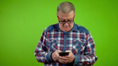 Parmakları hızlı mesaj atan son sınıf öğrencisi akıllı telefonuyla sohbet ediyor. Olgun insan telefonunda iki parmağıyla enerjik bir şekilde mesaj yazar ve yazışmaları yönetir. Yeşil ekran. Krom anahtar.