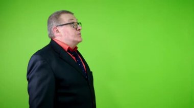 Siyah takım elbiseli komik kıdemli adam başparmağını sallıyor ve başını sallıyor. Olgun bir adam iyi sonuç ya da kaliteye güven belirtisi gösterir. Yeşil ekran. Krom anahtar.