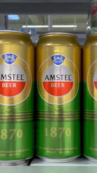 キエフ ウクライナ 2024年2月2日 アムステルビールのブランドは 販売のためのスーパーマーケットの棚に缶詰に積まれました アルコール飲料店のビールボトルがたくさんある棚 クローズアップ バーティカル — ストック動画