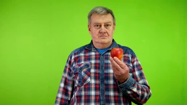 ポジティブな上級男性は 熟したリンゴと親指が果物の利点を肯定していることを示しています 成熟した人は リンゴが優れた健康的なベジタリアンやビーガンダイエットだと信じています グリーン スクリーン クロマキー — ストック動画