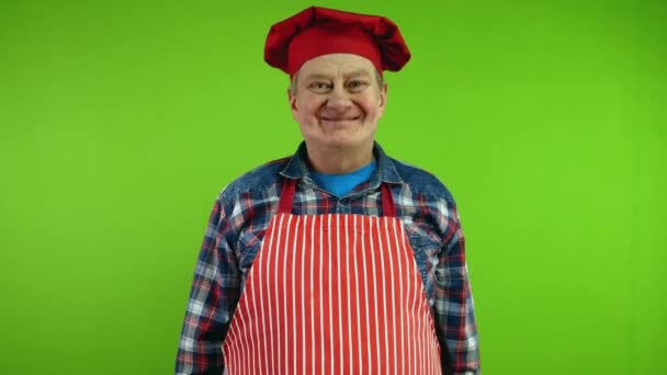 穿着红围裙的高级主厨看着摄像机点头回答是的 成熟的厨师给出了肯定的答案 点头表示同意 绿色屏幕 — 图库视频影像