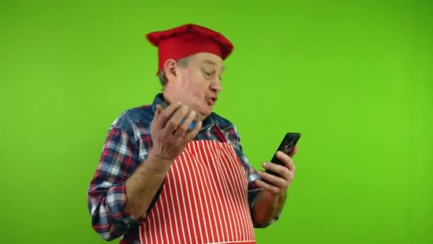 Starszy Kucharz Czerwonym Fartuchu Rozmawiający Kamerą Telefoniczną Różnych Rzeczach Swoim — Wideo stockowe