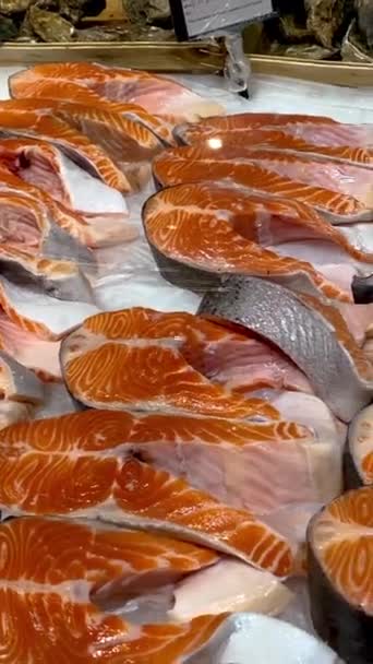 新鮮なスライスされた生のサーモンの部分は販売のための魚市場の冷蔵庫のカウンターの氷にあります スーパーマーケットのシーフードセクションで販売されている美味しく健康的な赤い魚 クローズアップ — ストック動画