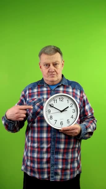大きな時計を指し ジェスチャーの時間がお金であることを示しています 成熟した人は 仕事やビジネス 人生における時間の制御時間を示しています グリーン スクリーン クロマキー バーティカル — ストック動画