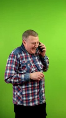 Son sınıf öğrencisi cep telefonuyla konuşuyor ve komik bir şakaya çılgınca gülüyor. Olgun insan akıllı telefonuyla komik bir konuşma yapıyor. Yeşil ekran, krom anahtar. Dikey.