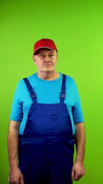 Arkadaş canlısı kıdemli tamirci kameraya bakıyor ve gülümsüyor. Basit insan mutluluğu kavramı ve başarılı, sosyal iyi niyet. Yeşil ekran. Krom anahtar. Dikey.