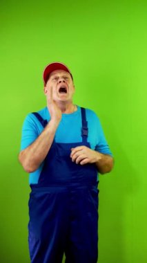 Tulum giymiş üst düzey bir tamirci mola sembolü gösteriyor ve herkese jest diyor. Olgun işçi işi bırakır ve mola için etrafındaki herkesi toplar. Yeşil ekran. Krom anahtar. Dikey.