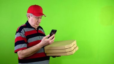 Olgun teslimatçı boş reklamlar yapıyor akıllı telefon ve gülümsüyor. Üniformalı ve beyzbol şapkalı olgun işçi elinde fotokopi alanı olan yeşil ekran cihazı tutuyor. Yeşil ekran. Krom anahtar.