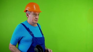 Tulum giymiş, tuvalet pompasını göstermekle tehdit eden, yumruğunu sallayan huysuz bir işçi. Saldırgan öfkeli tamirci çatışma sırasında yumruğunu havada sallıyor. Yeşil ekran, krom anahtar.