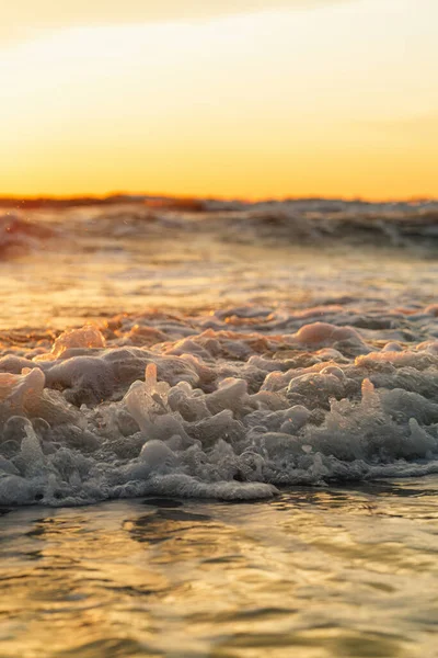 Beautiful view of the sea waves during golden sunset. Close-up.