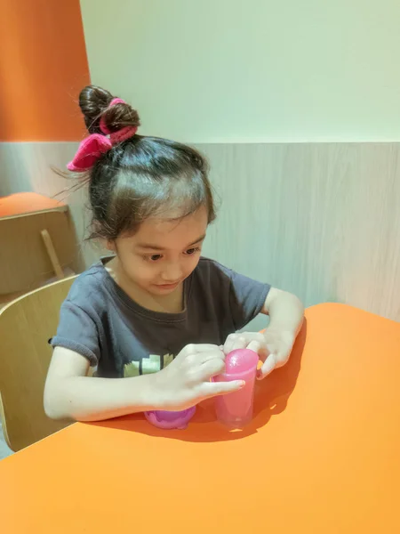 Маленькая Девочка Играет Розовой Блестящей Слизью Столе Ресторане — стоковое фото