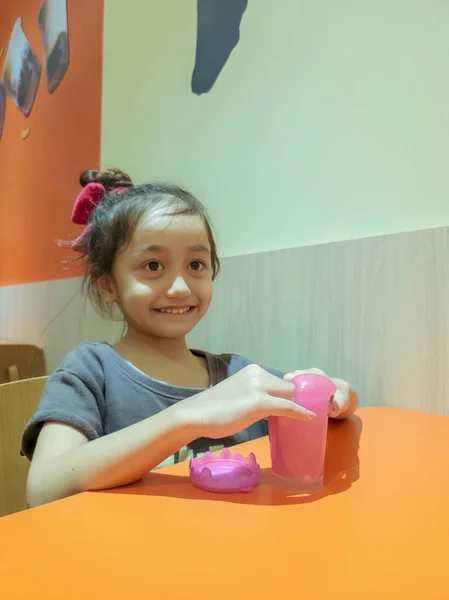 Küçük Kız Restoranın Masasında Pembe Parlak Sümükle Oynuyor — Stok fotoğraf