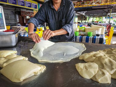 Selangor, Malaysia - June 4, 2022 Making Roti Parata or Roti canai with curry sauce - popular Malaysian breakfast