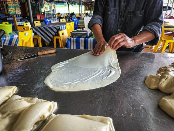 Making Roti Parata or Roti canai with curry sauce - popular Malaysian breakfast