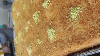 Geleneksel Arap tatlıları, restoranda yakın plan kunafa yemeği. El bilgisayarı, dikey video