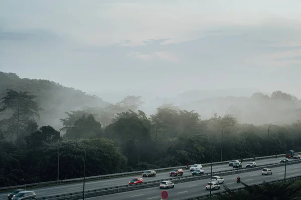 日の出の忙しい高速道路近くの霧の中で熱帯雨林の山々 美しい背景 — ストック写真