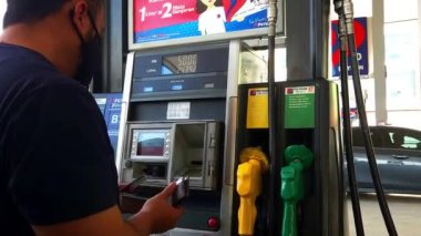  Bangi, Malezya - 28 Nisan 2022 Petron benzin istasyonunda kredi kartıyla bir arabaya yakıt ikmali yapan adam