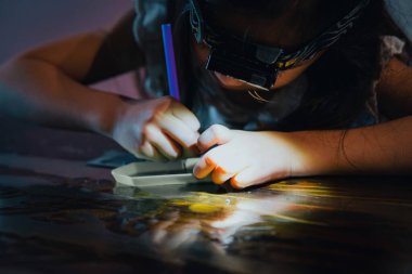 Pasting gemstones, a little girl is making artwork with her own hands.