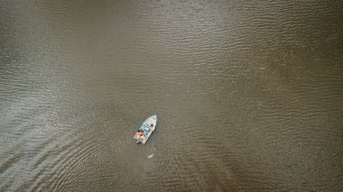 Gölün karanlık sularında yüzen bir teknenin drone görüntüsü.