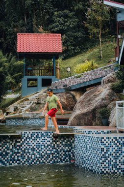 Tatil köyünde havuzda yürüyen bir çocuk. Tatil boyunca yüzme ve su oyunları.