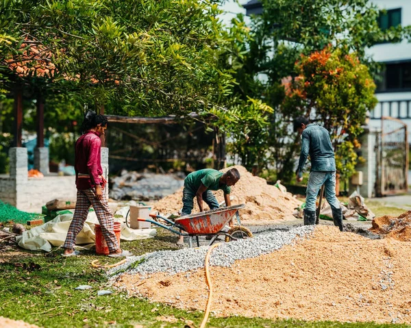 Selangor, Malezya - 21 Ekim 2023 Bir ev yenileme inşaatında betonla küreği karıştıran adam.