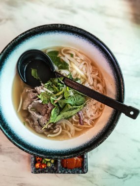 Büyük kaşık ile servis edilen Vietnam usulü eriştenin üst görüntüsü.