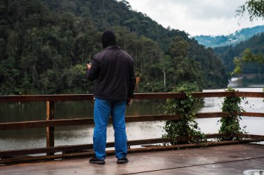 Fotoğrafçı ya da gezgin, küçük kamerasıyla fotoğraf çekmek için doğada duruyor..