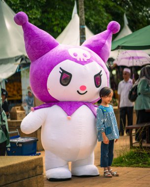 Putrajaya, Malaysia - September 19th, 2024: Kuromi mascot with a child on the street at a morning market.  clipart