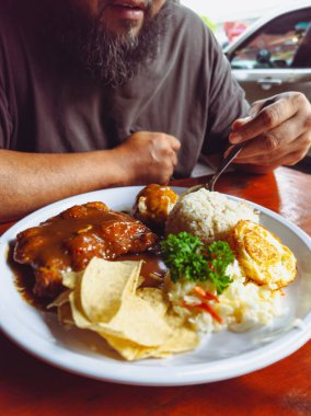 Tavuklu pirzola, pilav ve yumurta sakallı bir adam tarafından yenir..