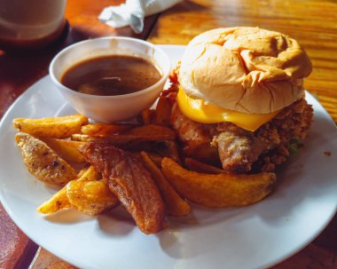 Klasik çizburger, ahşap masada beyaz tabakta servis edilen fırında patates..