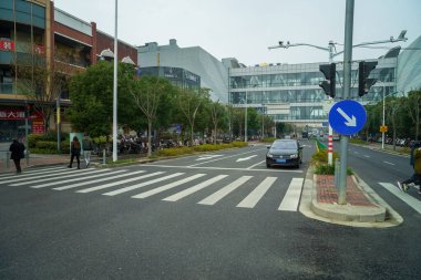 Şangay, Çin - 7 Aralık 2024 Pedestrian SML merkezinin yakınında arabasıyla karşıdan karşıya geçiyor.