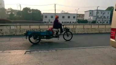 Şangay, Çin, 7 Aralık 2024 sabah erkenden yoldan geçen üç tekerlekli bir bisiklet. Yavaş çekim.