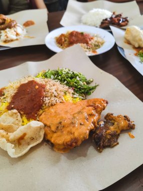 Nasi Kerabu olarak bilinen Asya yemekleri, mavi pirinç, otantik geleneksel sos, kızarmış balık, buğulanmış kırmızı biber ve biraz çiğ sebze ile servis edilir.