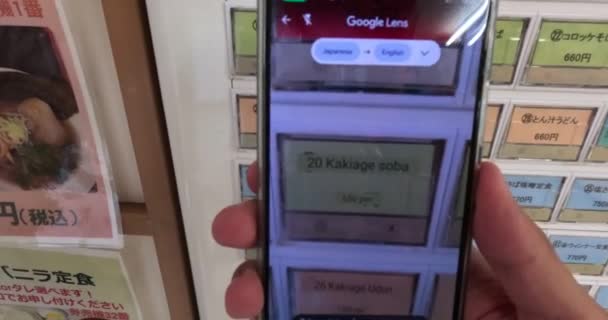 日本語から英語に自動販売機カフェメニューを翻訳しようとするスマートフォンを握る手 高品質の4K映像 — ストック動画