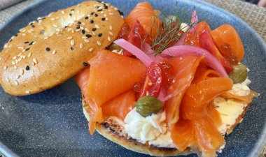 Seçici odak noktası, füme somon, ıspanak, kırmızı soğan, domates, avokado ve krem peynirli lezzetli simit. Hafif bulanık parçalı seçici odak