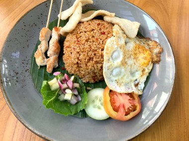 Dünyanın en iyi yemeklerinden biri Endonezya 'nın ünlü haber kanalı Kızarmış Pirinç Nasi Goreng tarafından sunulan kızarmış yumurta, tavuk satay ve kerupuk veya kraker ve turşu salatası ile servis edilir.