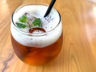 Köpüklü narenciye çayı, narenciyeli organik çay ve ahşap masanın üstünde bir bardak dolusu nane yaprağı.