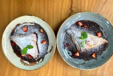 Elma tatlısı, krema şekeri, çilek parçaları ve çikolata sosuyla kaplanmış.