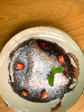 Elma tatlısı, krema şekeri, çilek parçaları ve çikolata sosuyla kaplanmış.