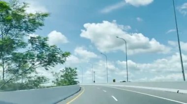 Otoyol boyunca ya da paralı yol altyapısında mavi gökyüzü ve beyaz bulutlu POV görüntüsü ile güzel boş yol videosundan geçen bir kameradan çekiliyor.