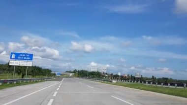 Otoyol boyunca ya da paralı yol altyapısında mavi gökyüzü ve beyaz bulutlu POV görüntüsü ile güzel boş yol videosundan geçen bir kameradan çekiliyor.