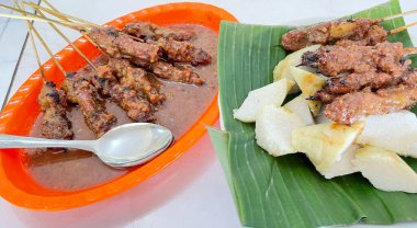 Fıstık sosu ve muz yaprağında pirinç keki ile servis edilen kömürün üzerinde ızgara yapılmış çok lezzetli sığır eti satay eti.