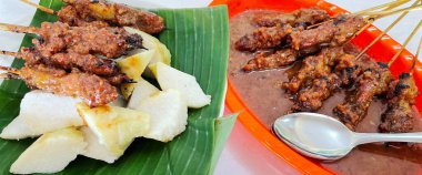 Fıstık sosu ve muz yaprağında pirinç keki ile servis edilen kömürün üzerinde ızgara yapılmış çok lezzetli sığır eti satay eti.