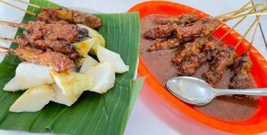 Fıstık sosu ve muz yaprağında pirinç keki ile servis edilen kömürün üzerinde ızgara yapılmış çok lezzetli sığır eti satay eti.