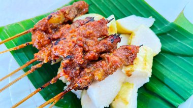 Fıstık sosu ve muz yaprağında pirinç keki ile servis edilen kömürün üzerinde ızgara yapılmış çok lezzetli sığır eti satay eti.