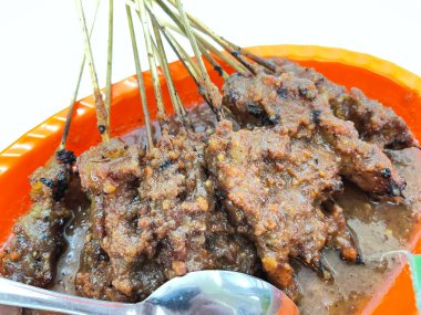 Fıstık sosu ve muz yaprağında pirinç keki ile servis edilen kömürün üzerinde ızgara yapılmış çok lezzetli sığır eti satay eti.