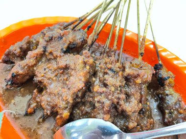 Fıstık sosu ve muz yaprağında pirinç keki ile servis edilen kömürün üzerinde ızgara yapılmış çok lezzetli sığır eti satay eti.