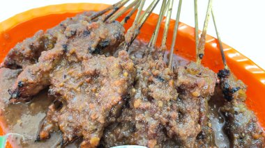 Fıstık sosu ve muz yaprağında pirinç keki ile servis edilen kömürün üzerinde ızgara yapılmış çok lezzetli sığır eti satay eti.