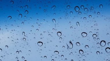 Su damlacıkları cam yüzey üzerinden mavi gökyüzüne karşı perspektif ile multimedya içeriği için iyidir